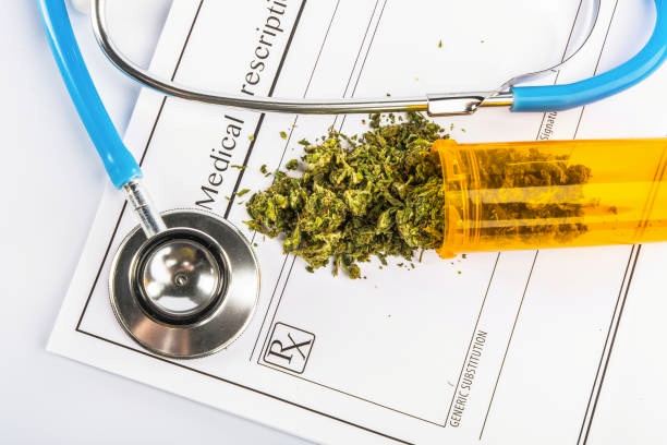 Close up of medical marijuana in yellow pill bottle with stethoscope on doctors prescription for weed
